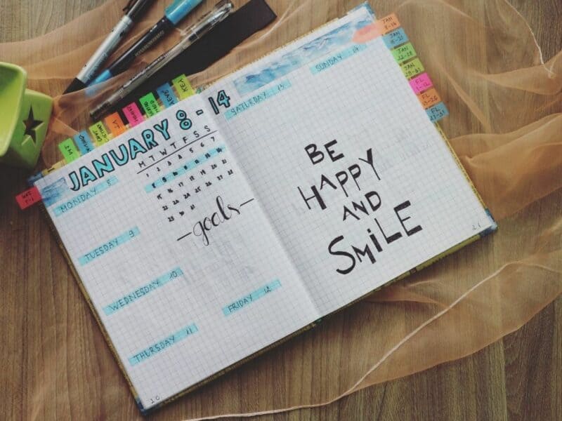 colorful journal laying on a table with the words "be happy and smile"