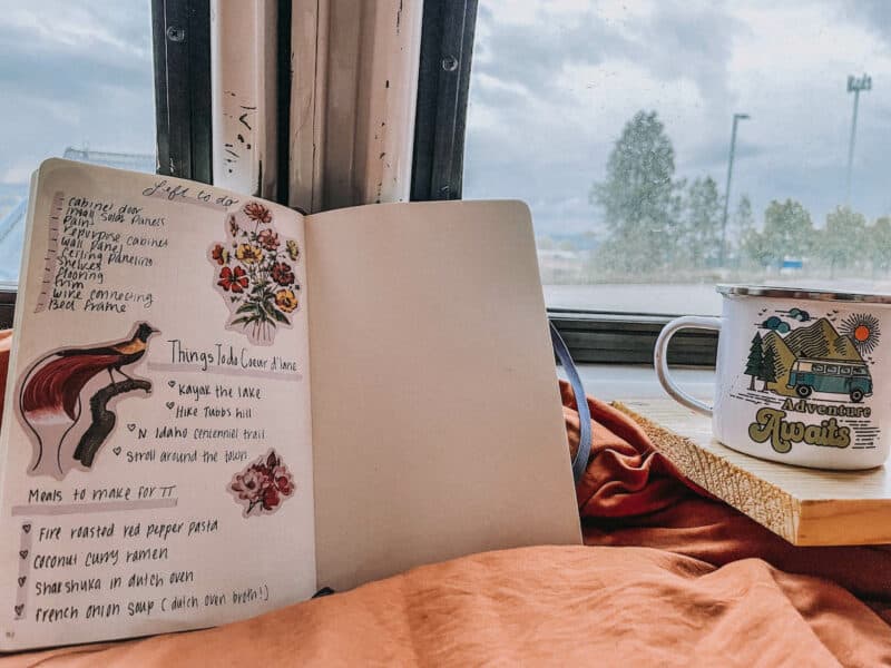A bullet journal spread opened in a van showing van life and summer bucket list ideas while in Coeur d'Alene Idaho