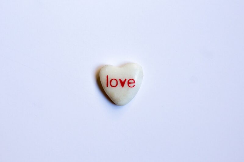 The word Love written in red on a small white heart-shaped rock. Love is a great word month word to focus on