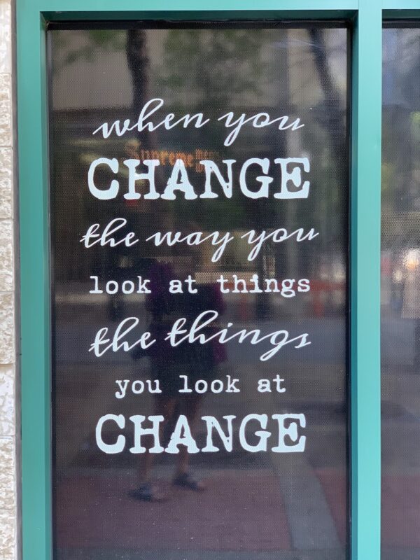Inspirational message in a store window that says "when you change the way you look at things, the things you look at change." Reframing is one of several popular positive thinking exercises you can do in your journal